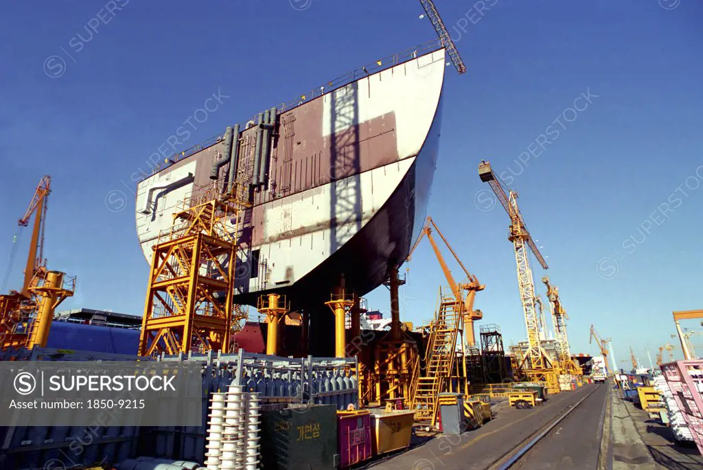 South Korea, Pusan, Dae-Woos New Ship Building Yard With Ship Section Raised On Scaffolding Surrounded By Cranes