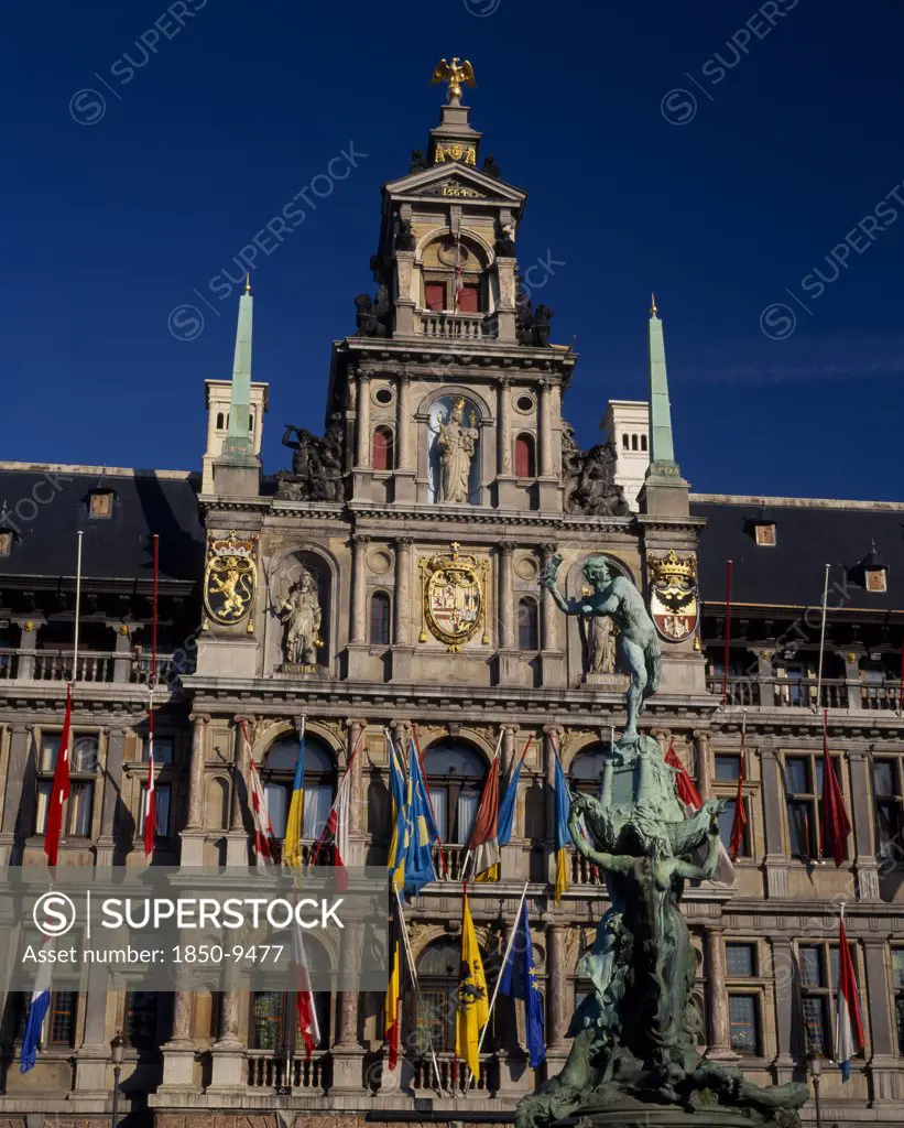 Belgium, Flemish Region, Antwerp, Grote Markt Or Main Square.  The Brabo Fountain With The Town Hall Facade Hung With Flags Behind .