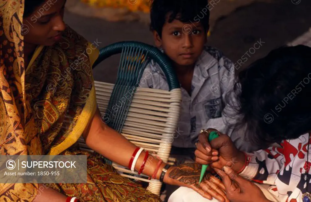 India, Religion, Hindu, Woman Having The Palms Of Her Hands Decorated In Henna For Her Wedding With Small Boy Onlooking