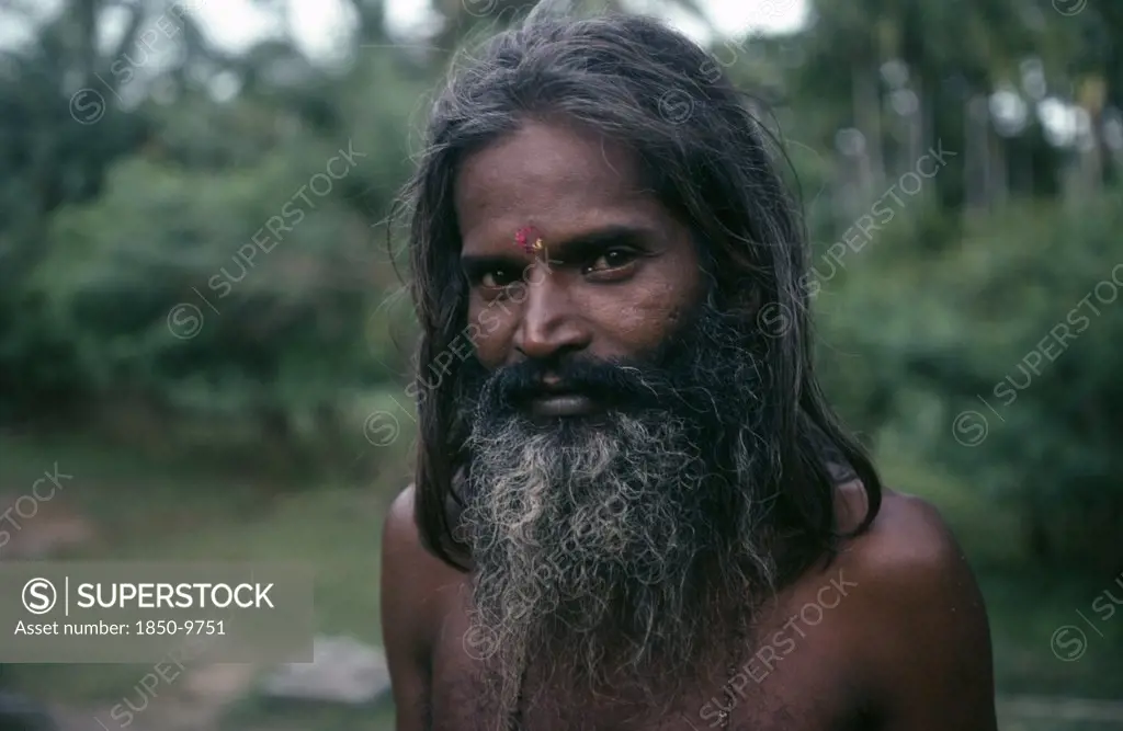 Sri Lanka, People, Men, Portrait Of Man With Beard And Long Hair Standing Within Green Landscape.