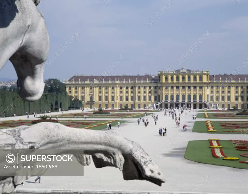 Austria, Lowe Austria, Vienna, Schonbrunn Palace And Tourists Walking In The Formal Gardens With A Stone Equestrian Statue In The Foreground