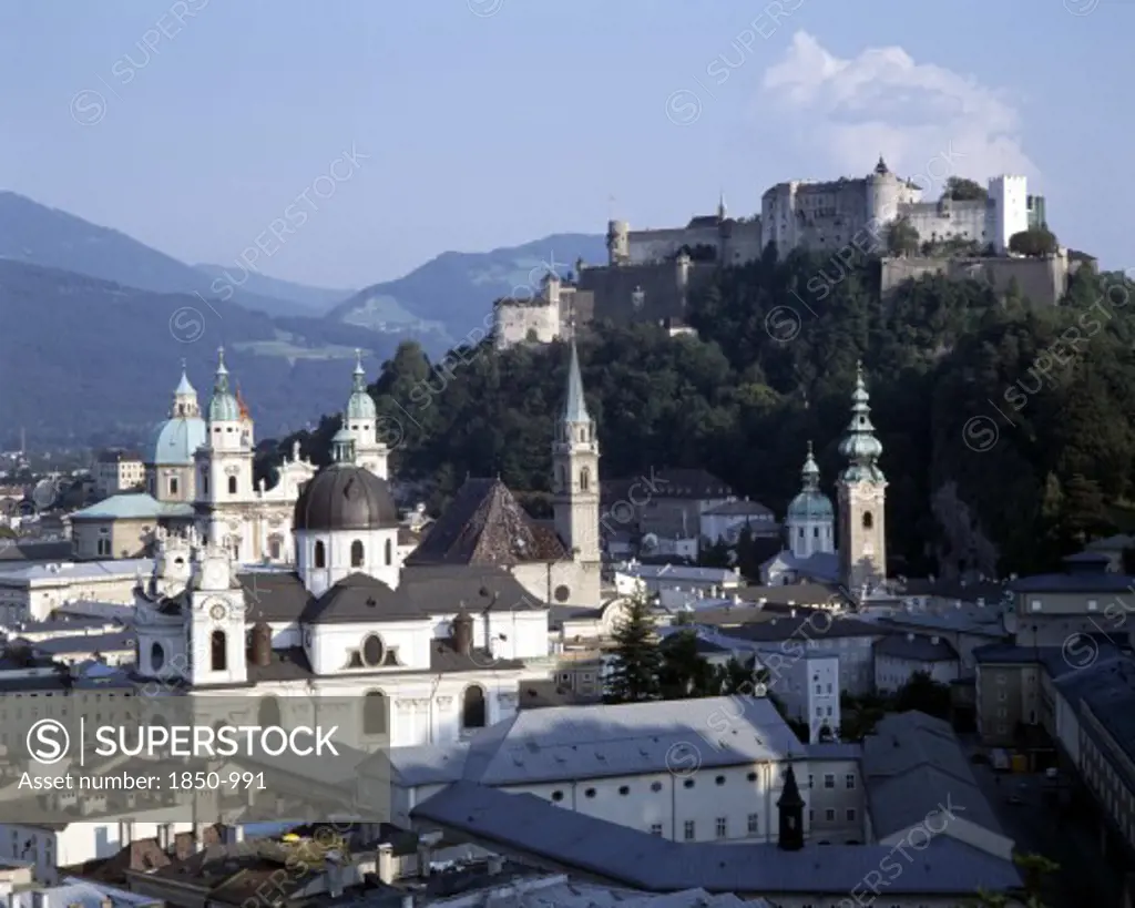 Austria, Salzburg Province, Salzburg, Hohensalzburg Fortress Beyond Town Rooftops With Wooded Hills Behind