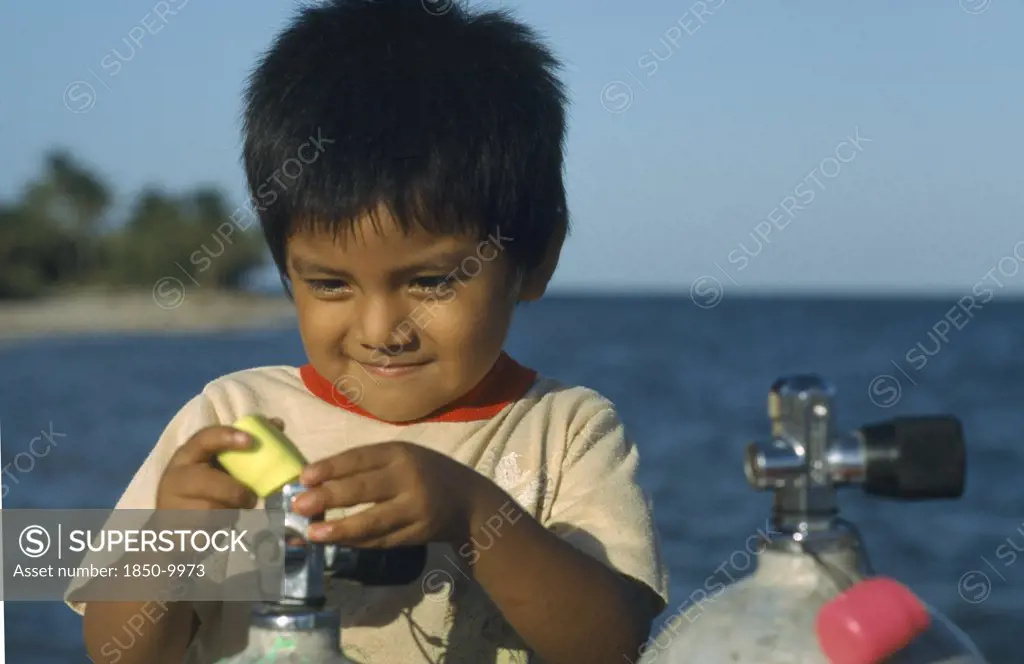 Belize, Placencia, Local Boy Playing With Dive Tanks