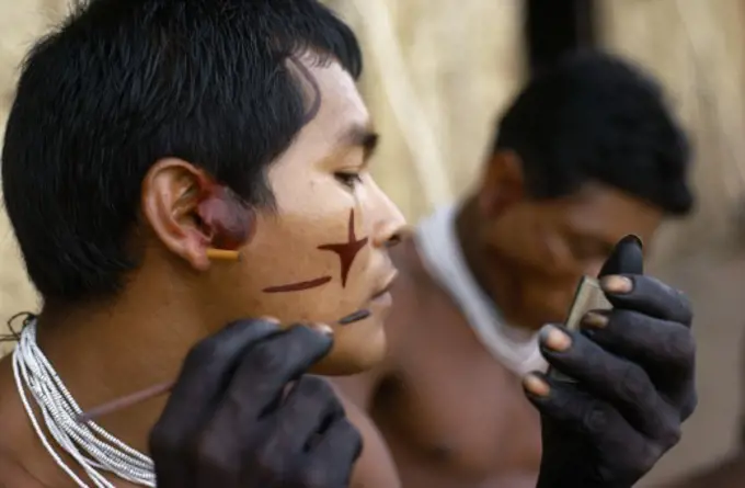 Colombia, North West Amazon, Tukano Indigenous Tribe, 'Barasana Men (Sub Group Of Tukano) Decorating Their Faces With Red Achiote Facial Paint For Ceremonial Dance/Festival Hands, Wrists Blackened With Dark Purple/Black Juice From We Leaves Wearing Necklaces Of Small White Glass Trade Beads '