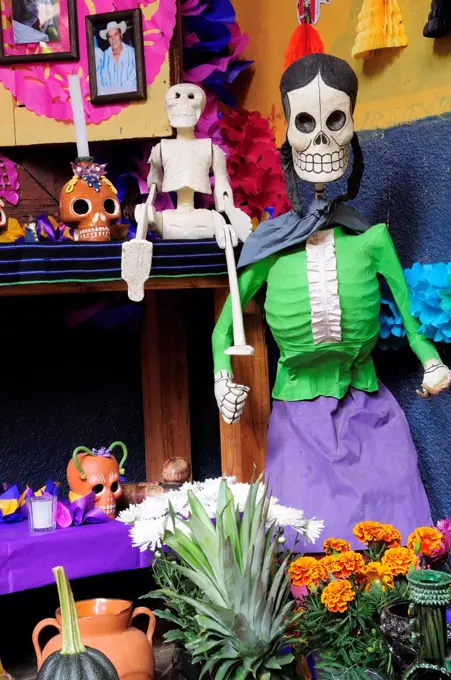 Mexico, Michoacan, Patzcuaro, Dia de los Muertos Day of the Dead altar with skeleton figures flowers and colourful paper decorations.
