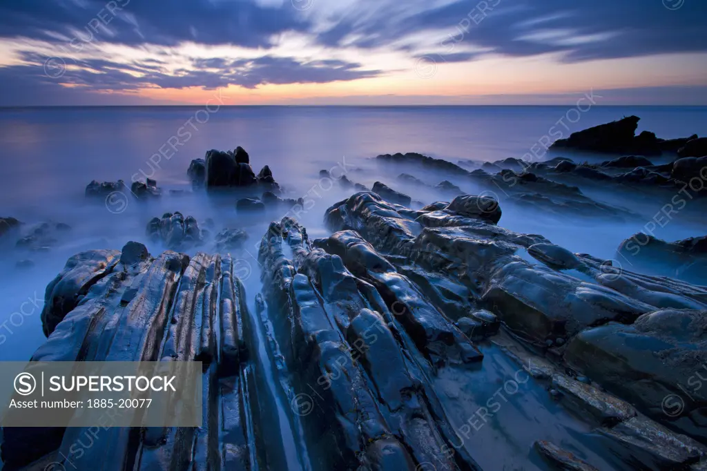 UK - England, Cornwall, Sandymouth, Rock ledges in sea at dusk