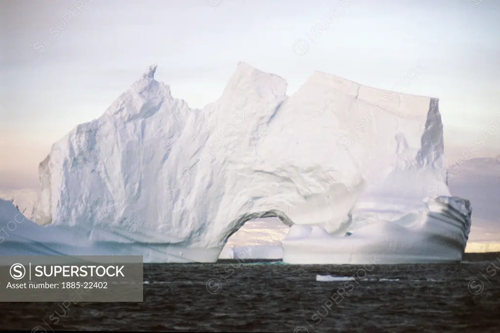 Antarctica, Antarctic Peninsula, Iceberg showing wind shaped arch and ocean water and sky