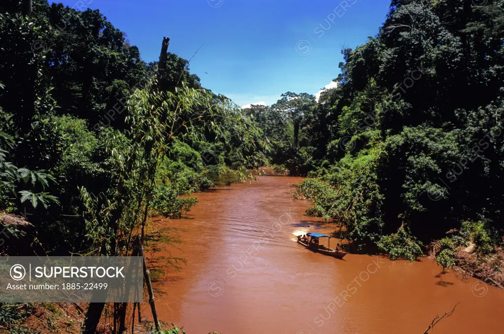 Peru, Red Amazon tributary River Manu in Manu National Park - showing rainforest canopy and mineral coloration after rains