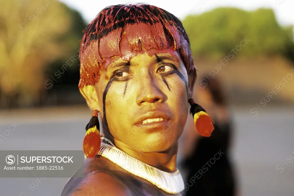 Brazil, Xingu Amazon tribesmen  with face decorated in jempapo and red-yellow paint made form urucum seeds and hear color form rurucum mixed with water and mud, face in traditional black patterns dyed with jemipapo plant, necklace from traditional white shell beads