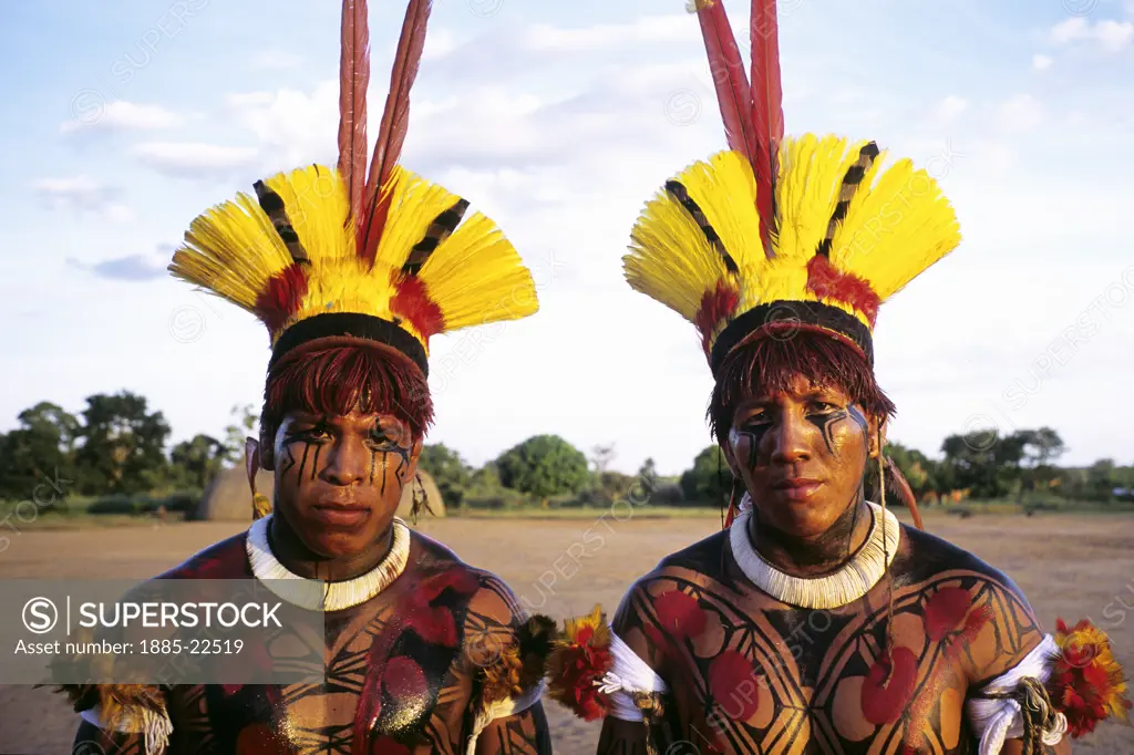 Brazil, Xingu Amazon tribesmen  with face decorated in body paint including urucum and yellow tucan feathers and natural dyes in traditional patterns