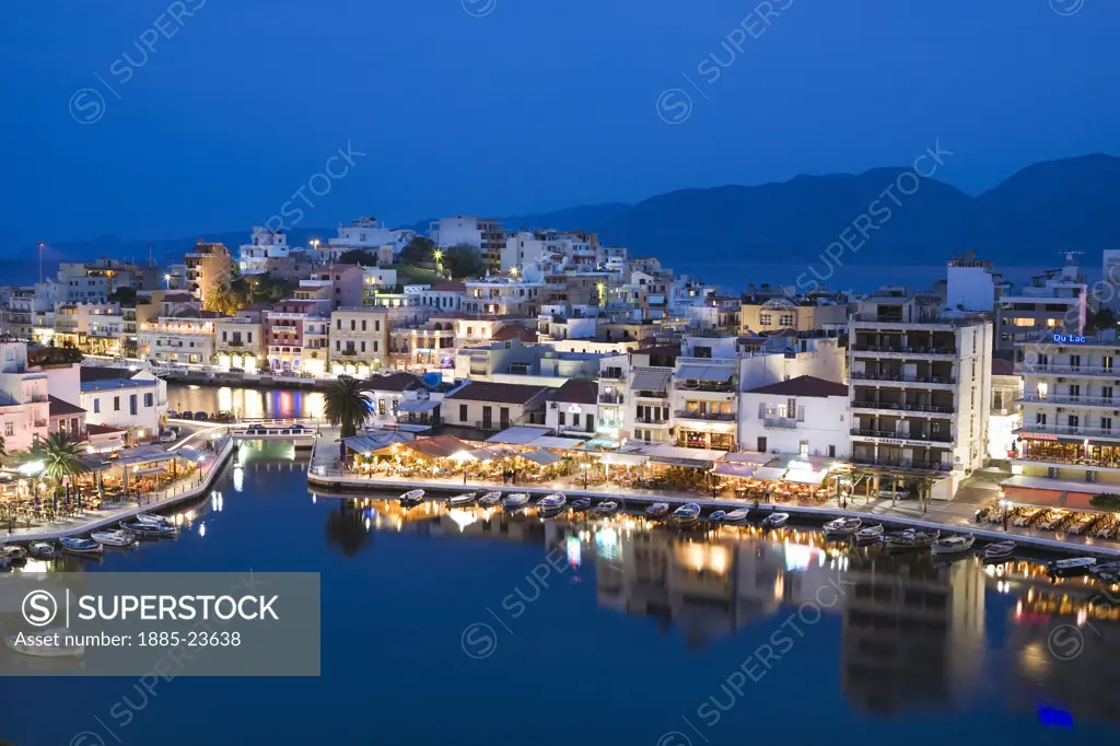Greek Islands, Crete, Ayios Nikolaos, View over harbour at dusk with restaurants