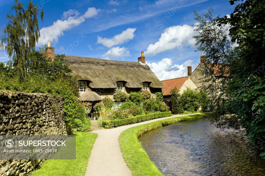 UK - England, Yorkshire, Thornton le Dale, Thatched cottage by a stream