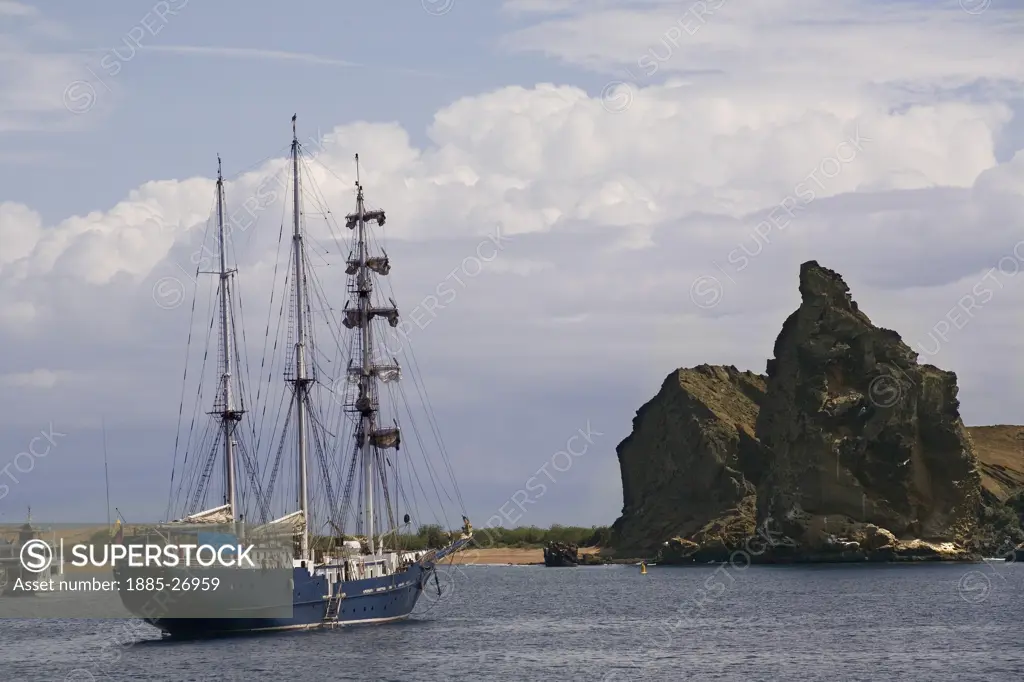 Ecuador, Galapagos Islands, Bartolome Island, Rock pinnacle and sailing ship