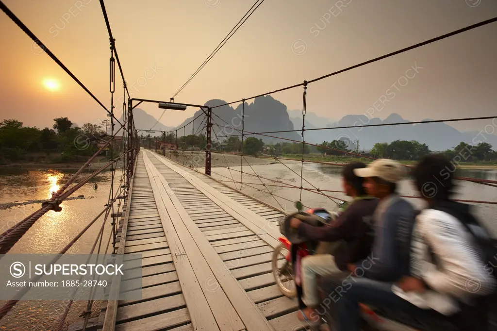 Laos, Vientiane, Vang Vieng, a motorcycle carrying 3 crossing the bridge over the Nam Song River at Vang Vieng, Laos