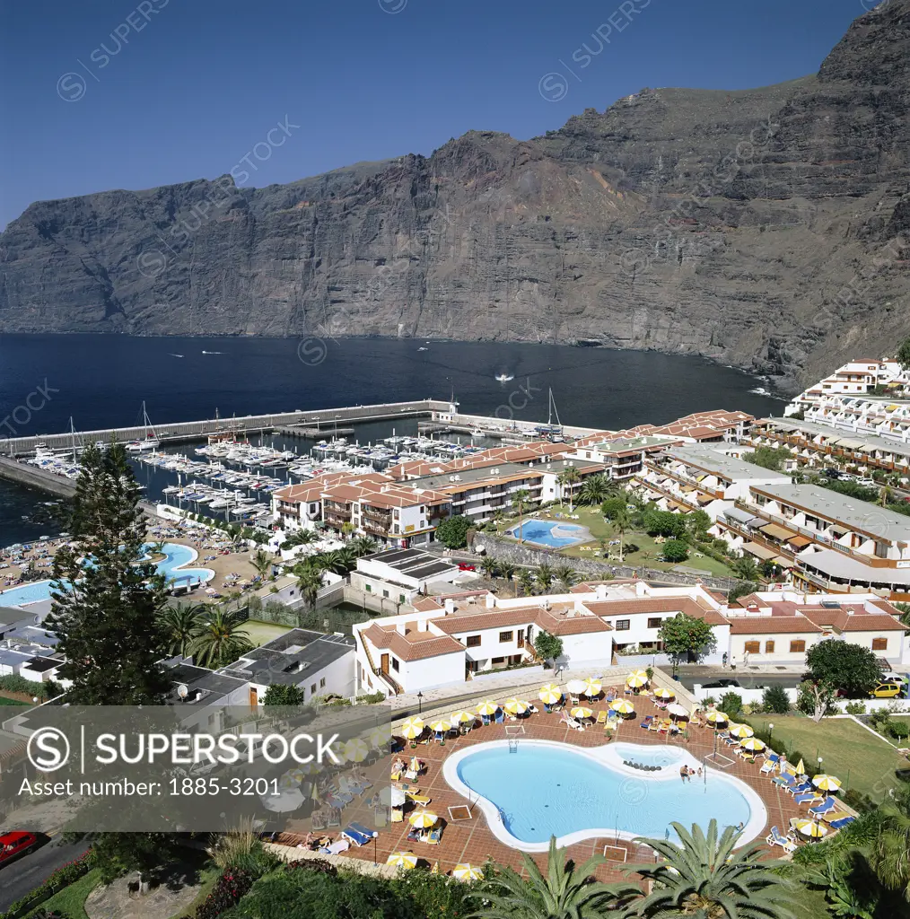 Canary Islands, Tenerife, Los Gigantes, View over hotels, pools and harbour, to cliffs in b/g