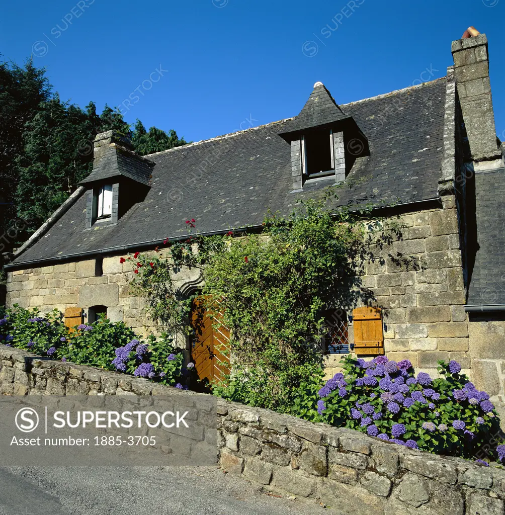 France, Brittany, Locronan, Cottage with stone wall and flowers