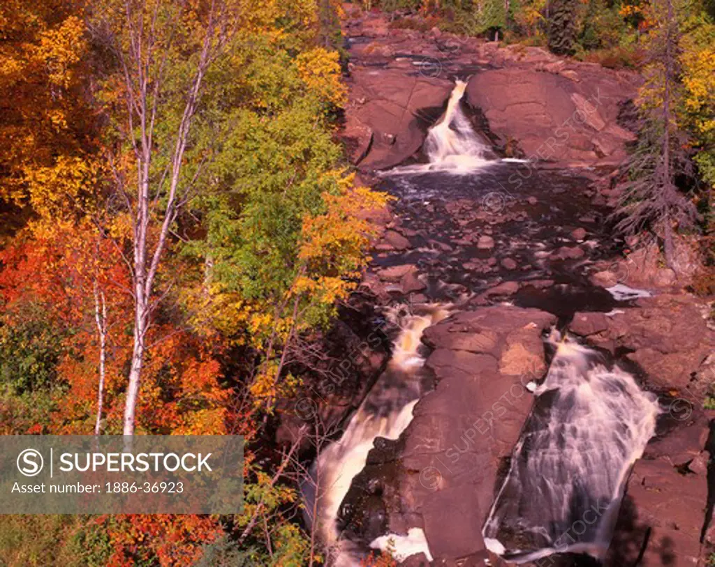 Beaver River cascades through bedrock ledges and boulders, autumn on Lake Superior in northern Minnesota, USA.