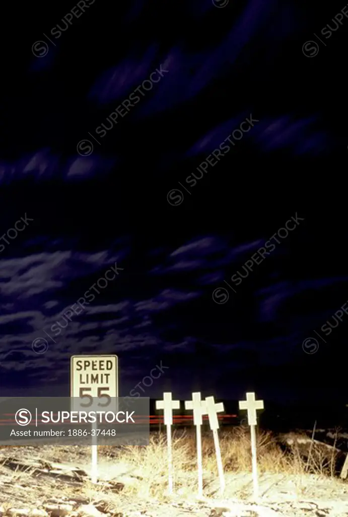 Roadside accident memorial crosses and speed limit sign on U.S. Highway 10 in central Montana.