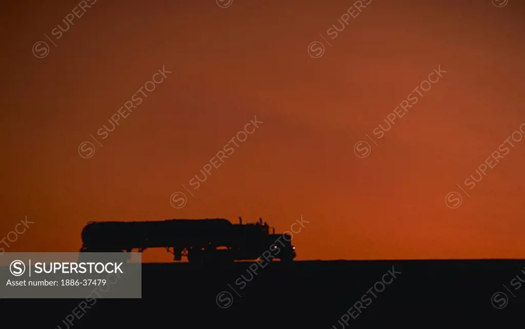 Tanker truck silhouette at sunrise on I-90 interstate highway.