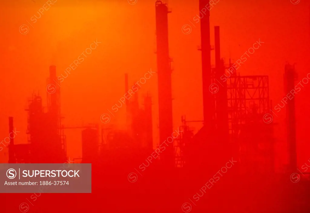 Oil refinery silhouette with sunset in background, New Mexico.