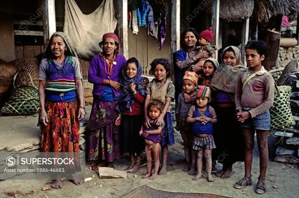 A smiling GURUNG FAMILY, mostly female, in the yard of their traditional FARM HOUSE - ANNAPURNA REGION, NEPAL