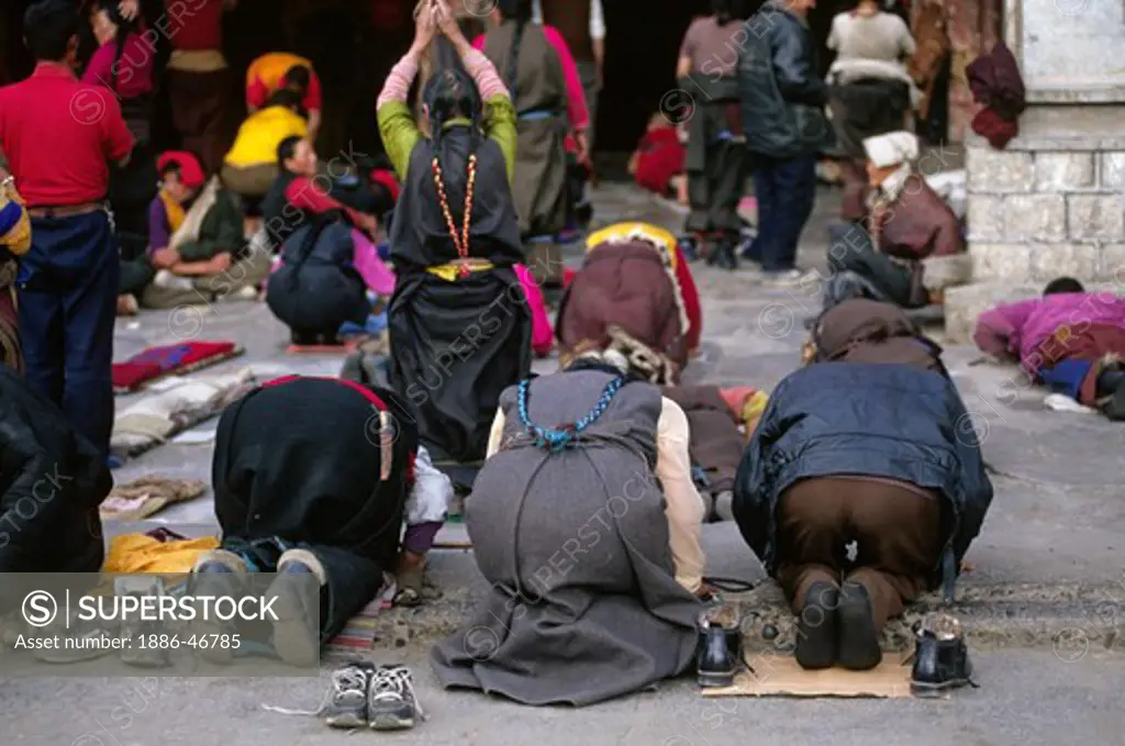 Devout BUDDHISTS prostrate in front of the JOKHANG, TIBET'S holiest temple, built in the 7th Century by KING SONGTSEN GAMPO - LHASA, TIBET