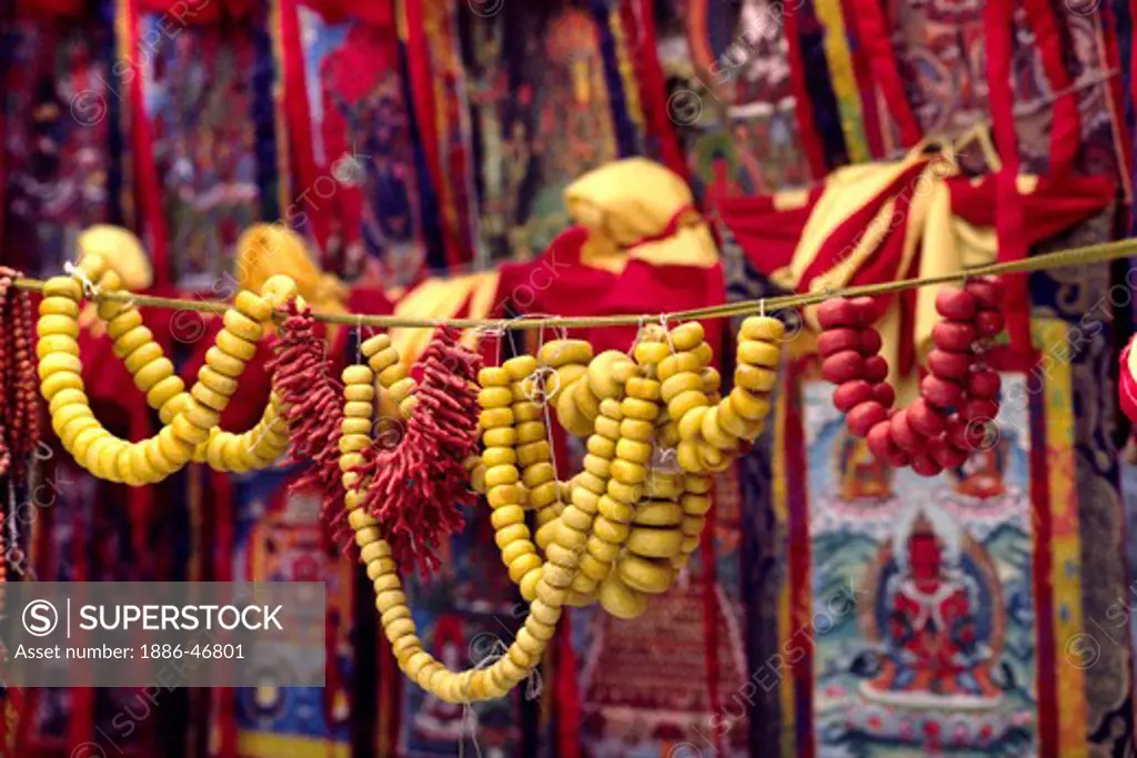 Strings of AMBER & CORAL are proffered for sale along the BARKHOR the TIBETAN Bazaar in LHASA, TIBET