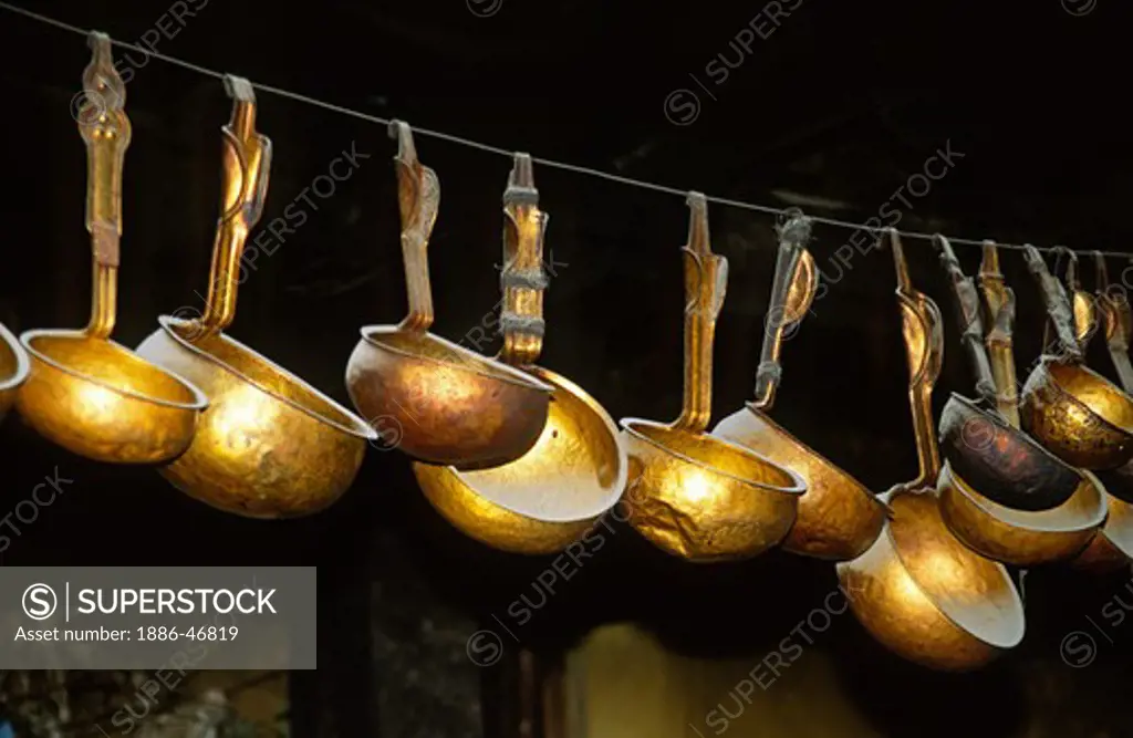 COPPER SERVING SPOONS hang in a kitchen at DREPUNG MONASTERY which was built in 1416 AD - LHASA, TIBET