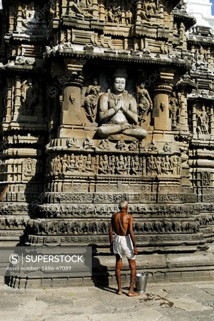 Old priest cleaning God Vishnu statue on temple wall  of  Aundhanagnath one of twelve Jyotirling Shiva temples Shivaling at Aundha near Nanded, Maharashtra, India