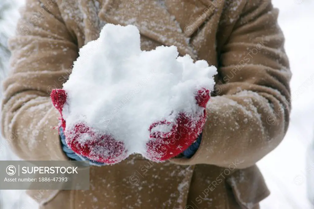 Lady with fresh snow in hand during snow fall
