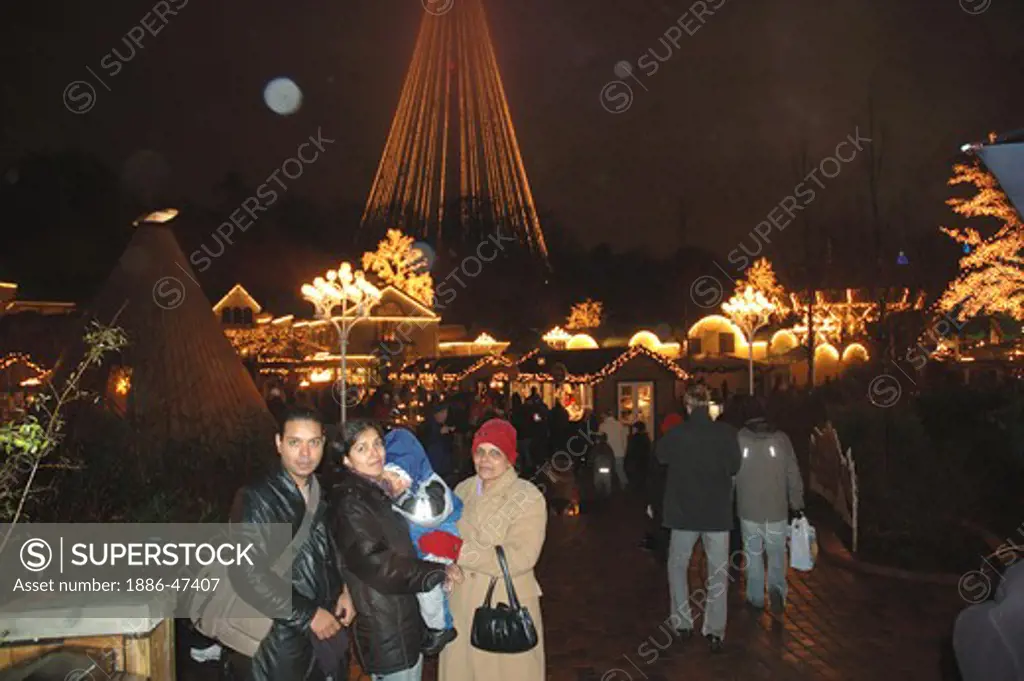 Family of husband, wife, son and mother of young lady at Liseberg, amusement park at night at Golthenborg, Sweden, MR # 468
