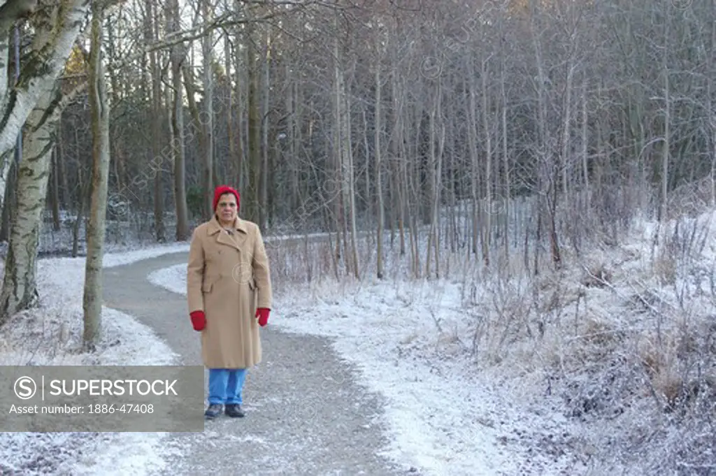 Old lady wearing winter cloths on forest path in Gothenburg, Sweden MR # 468