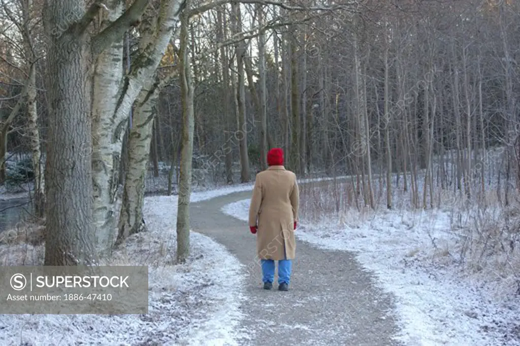 Old lady walking wearing winter clothes in forest in Gothenburg, Sweden MR # 468