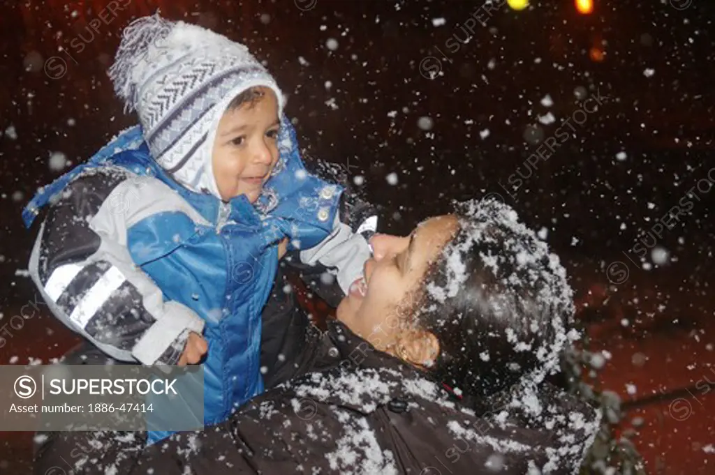 Mother lifting son of two years old in first snowfall of winter, December, 2006 at Gothenburg, Sweden, MR # 468