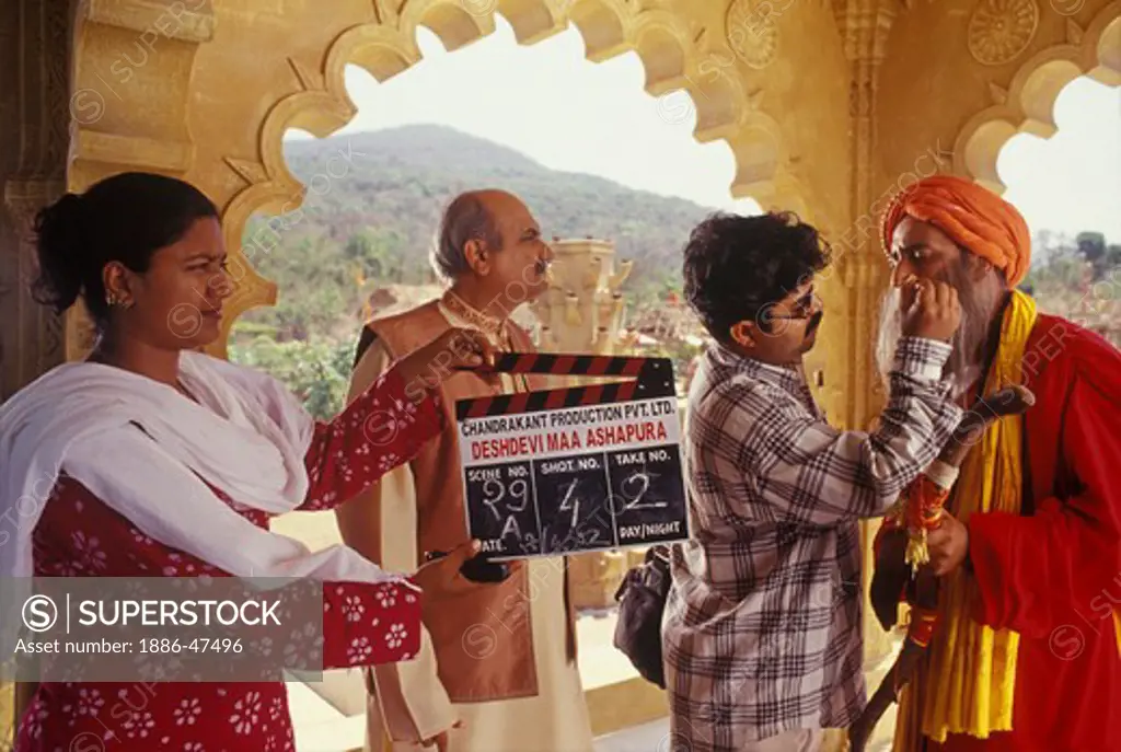 A make-up artist giving final touches for a Bollywood film shoot and a clapper girl holds the clapper board before the camera ; film city ;  Mumbai Bombay ; Maharashtra ; India
