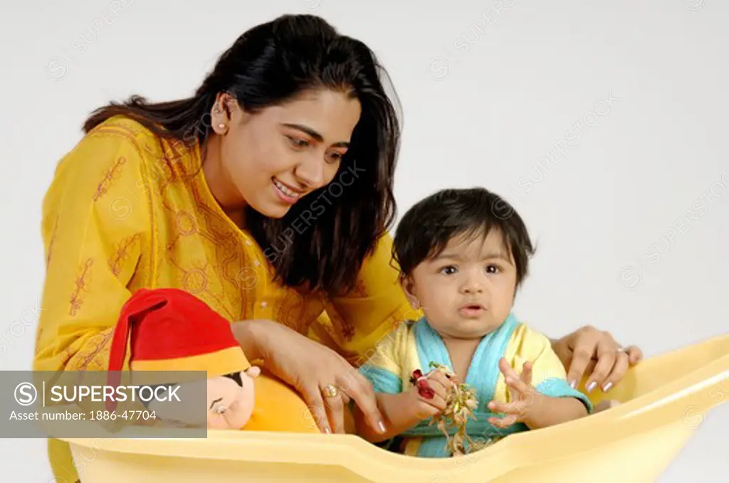 Indian Baby playing in yellow bath tub with mother ; MR