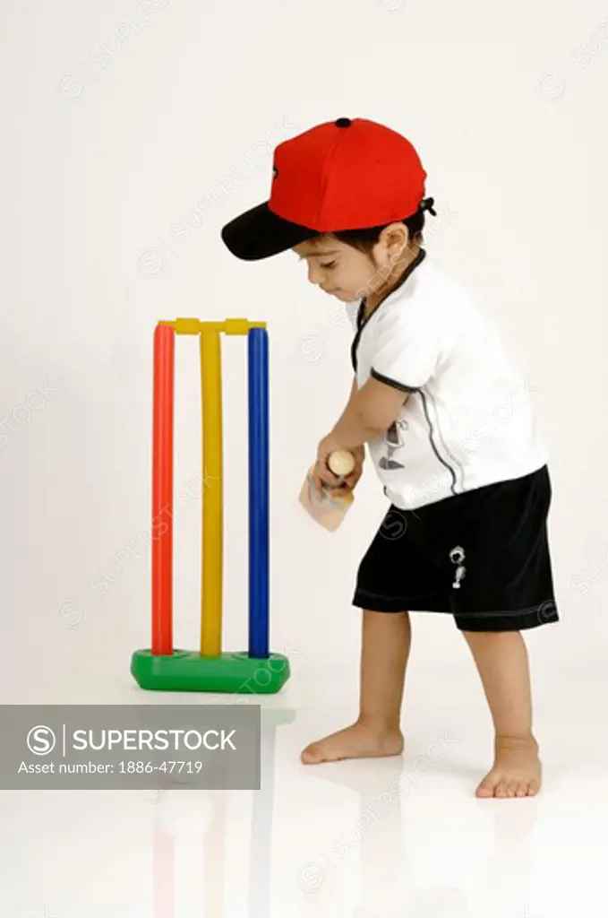 Indian Boy swinging the bat to hit the ball playing cricket ; MR