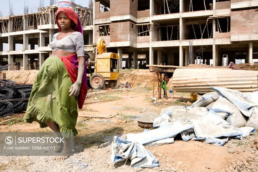 A pregnant women worker at a construction site with her hands and legs stained with cement ; Ahmedabad ; Gujarat ;  India