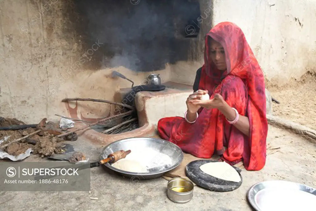 A  woman making wheat bread or rotis  on a fireplace  ; Rajasthan ; India