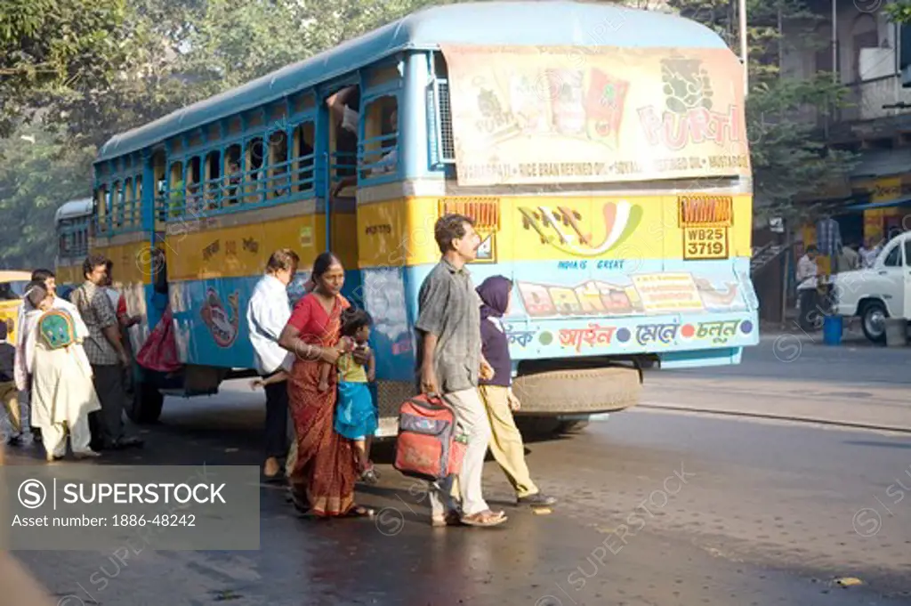 People crossing street behind blue bus ; Calcutta now Kolkata ; West Bengal ; India