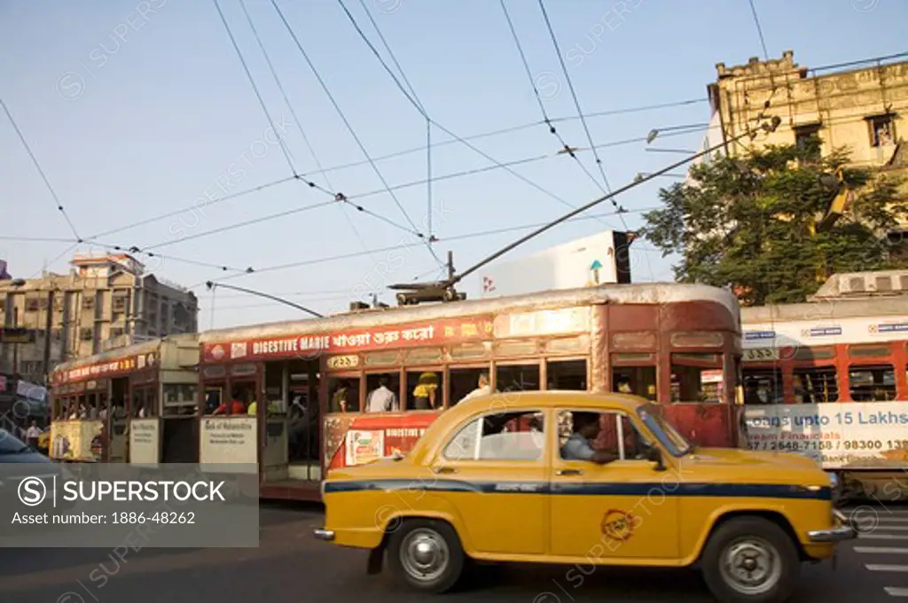 Tram in old way of commuting service and yellow color taxi on road ; Calcutta now Kolkata ; West Bengal ; India