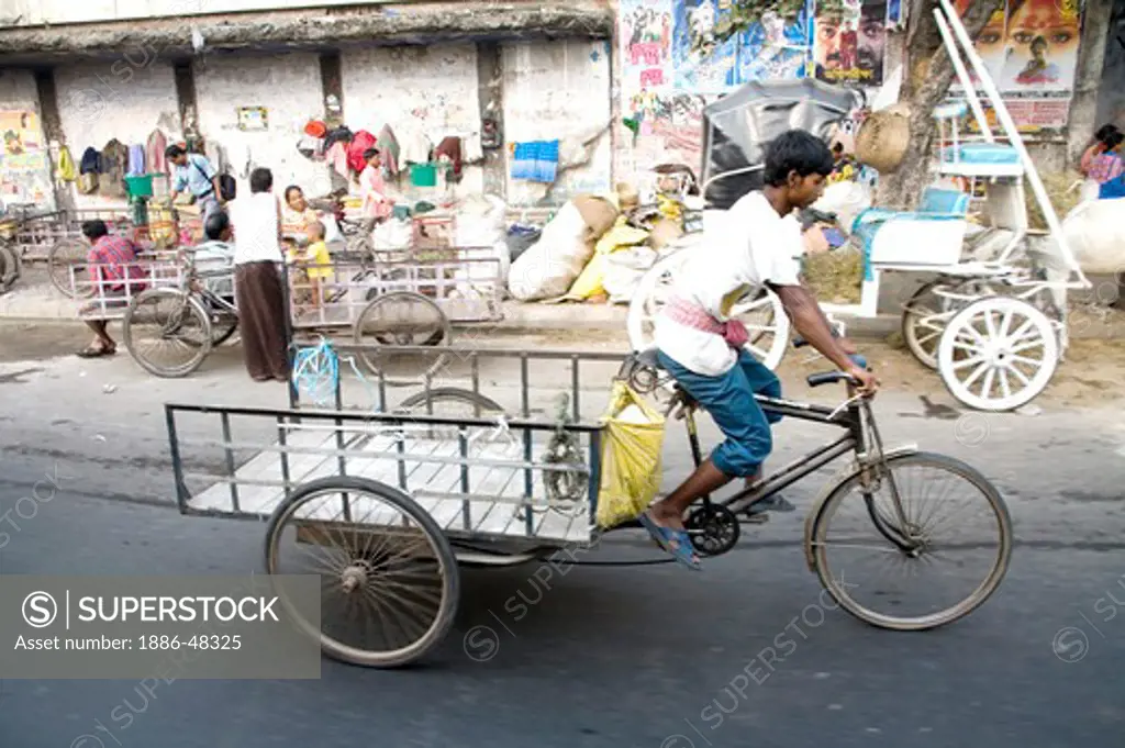Street scene ; cycle rickshaw rider riding empty vehicle ; Calcutta now Kolkata ; West Bengal ; India