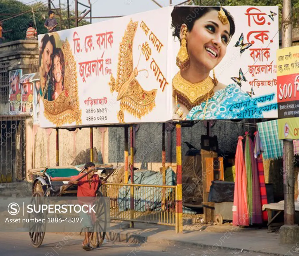 Indian street scene ; hand rickshaw puller passing at jeweler hording in bangla language ; Calcutta now Kolkata ; West Bengal ; India