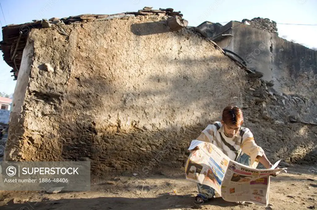 Rural man reading hindi language newspaper literacy in semi urban village Dilwara ; Udaipur ; Rajasthan ; India