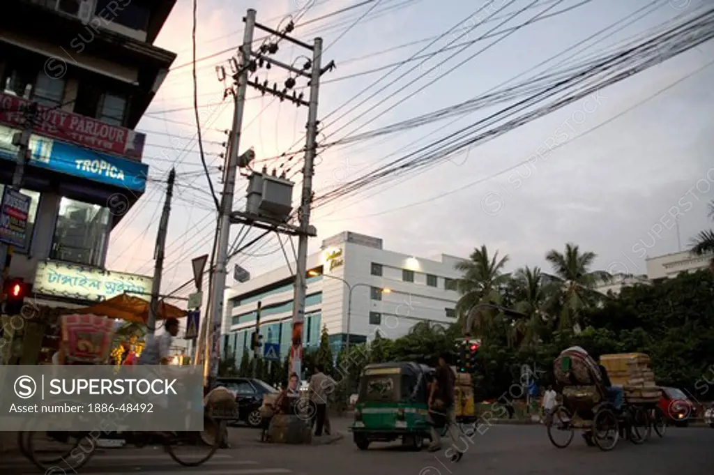 Evening street scene ; electric pole transformer on road criss cross wire ; Dhaka ; Bangladesh