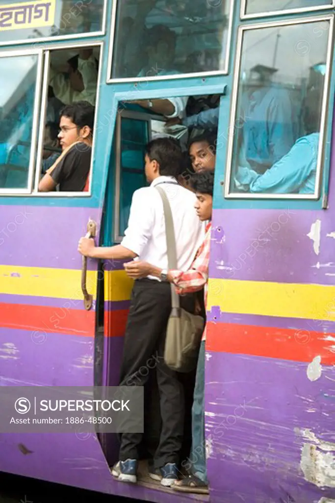 Public transport ; commuters standing at door of crowded bus ; Dhaka ; Bangladesh