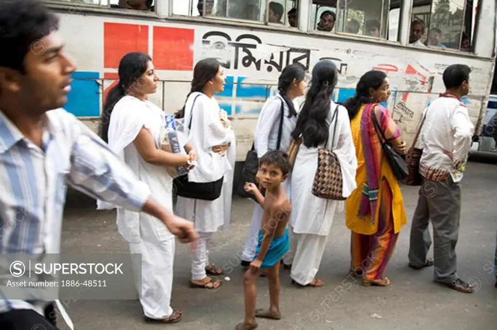 Street scene ; people standing in queue waiting for bus ; Dhaka ; Bangladesh