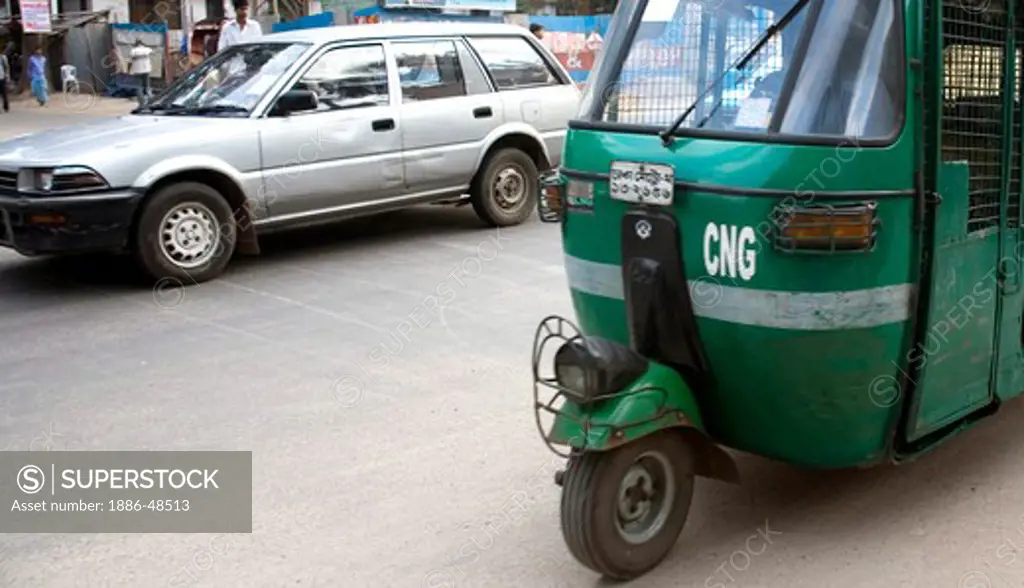 Street scene ; green auto rickshaw tempo and car on road traffic in Dhaka ; Bangladesh