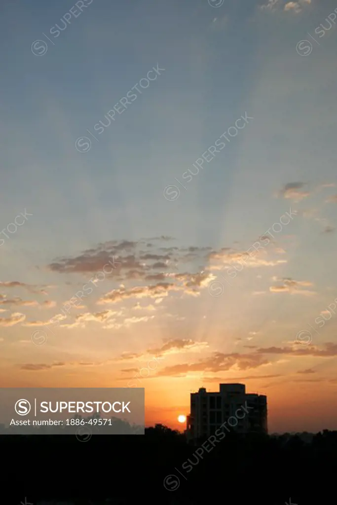 Glorious sunrise behind residential apartment with patchy clouds ; Pune; Maharashtra ; India