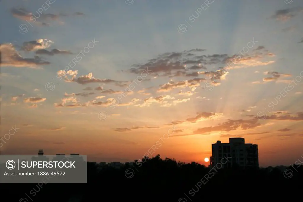 Glorious sunrise behind residential apartment with patchy clouds ; Pune; Maharashtra ; India